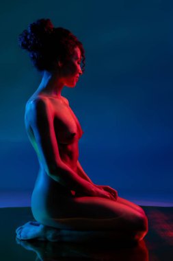 Bir kadın zarif bir şekilde poz verir yumuşak bir mekanda, zarif ve akıcı bir şekilde dans eder gibi..