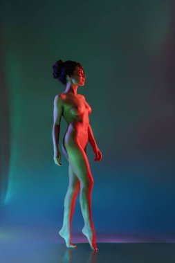 Bir kadın zarif bir şekilde dans duruşu sergiliyor, ışığını ve gölgelerini kullanarak formunu ön plana çıkarıyor. Çevre canlı renkler ve derinlik yaratır.