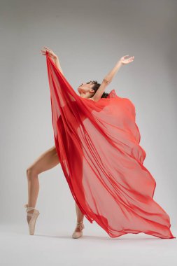 Üstsüz ve bale ayakkabılı bir dansçı, minimalist bir alanda zarifçe hareket eder, ışık, gölgeler ve hareketin akıcılığını gösterir..