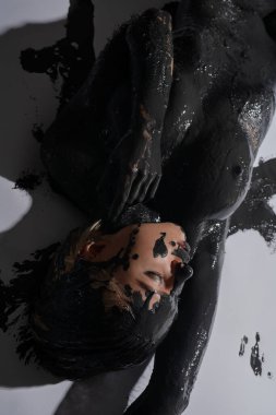 Beyaz arka planda zarif bir şekilde uzanan bir kadın. Karmaşık siyah boyalarla süslenmiş. Güzellik ve yaratıcılık sergiliyor..