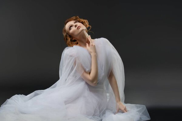 A stunning woman wearing delicate white lingerie poses in a graceful manner, exuding beauty and femininity.