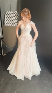Bir kadın sahne arkasına hazırlanıyor, göz kamaştırıcı gelinliğini bir moda etkinliğinde sergiliyor..