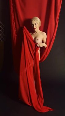 Bir dansçı zarif bir şekilde kırmızı bir kumaşla hareket eder, dinamik şekiller ve desenler yaratır..