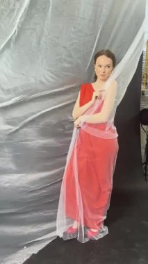 Stüdyoda zarif bir şekilde poz veren bir kadın moda ve sanat eserleri sergiliyor..