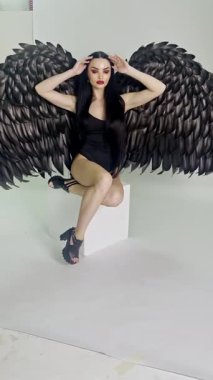 Yaratıcı bir güzellik stüdyosunda, bir kadın dikkat çekici bakışını ve eşsiz kanatlı aksesuarını sergilerken kendine güvenen bir şekilde poz verir..