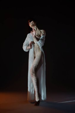 Bir kadın zarif bir şekilde iç çamaşırlarıyla dans eder, zarif pozlar verir. Sahne ışıklarının yumuşak parıltısı vücudunun her yerinde ilgi çekici gölgeler ve desenler yaratarak o anın sanatını arttırıyor..