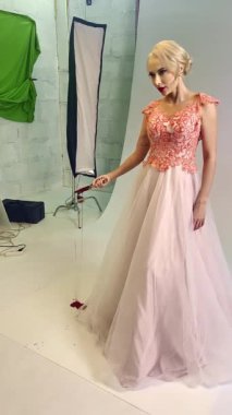 Bir manken, parlak bir stüdyo ortamında yumuşak ışıklandırmalı ve renkli arka planlı güzel bir elbise sergiliyor..