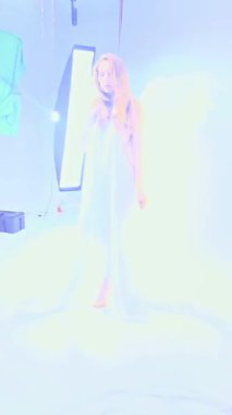 Stüdyoda, bir kadın zarif bir şekilde kumaş ve melek kanatlarıyla poz verir, modellik yeteneğinin altını çizer..