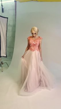 Bir manken, bir moda stüdyosunda çok güzel tasarlanmış bir elbise sergiliyor. Detaylarını vurguluyor..