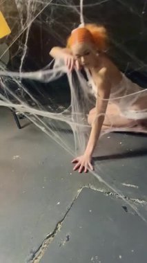 Canlı kırmızı özellikleri olan bir kadın, karmaşık bir ağ boyunca örüyor, karanlık bir ortamda güzelliği somutlaştırıyor..