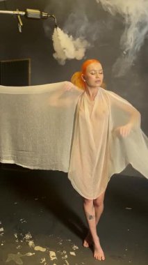 Kızıl saçlı bir kadın sanatsal yeteneklerini sergilemek için yaratıcı bir stüdyoda saf kumaşla çalışıyor..