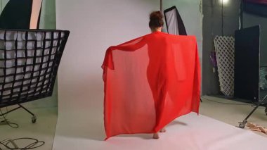 Çekici bir kadın zarif bir şekilde dans stüdyosunda poz veriyor. Canlı kırmızı elbisesi sanatsal ve büyüleyici ifadeler sergiledikçe akıyor. Stüdyo ayarı performansının güzelliğini artırıyor, zarafetini ve özgüvenini vurguluyor..