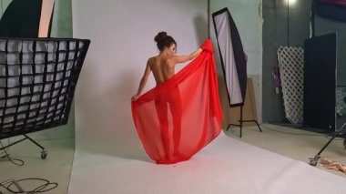 Çekici bir kadın dans stüdyosunda zarif pozlar ve ifadeler sergileyerek yeteneğini sergiliyor. Parlak kırmızı kumaş, dans ve yaratıcılığın özünü somutlaştırarak çevresiyle etkileşime girerken zarifçe akıyor..
