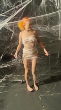 Çarpıcı kızıl saçlı bir kadın, eşsiz bir sanatsal düzende karmaşık bir ağ ile şakalaşıyor..