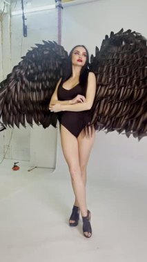 Kadın zarif bir şekilde şık bir stüdyoda poz veriyor, eşsiz kanatlı kıyafetinin altını çiziyor..