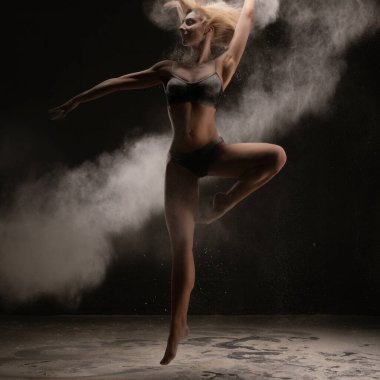 Bir dansçı karanlık bir ortamda zarifçe zıplar, tutku ve enerjiyle hareket eden bir toz bulutu yaratır..