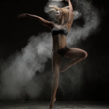 Karanlık bir odada ince sarışın kadın iç çamaşırı incelikle beyaz toz bulutu içinde atlama vurdu