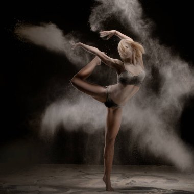 Bir dansçı karanlık bir ortamda güçlü bir poz verir. Etrafında un kıvrılır, zarafet ve hareket gücü sergiler..