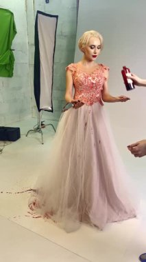 Bir model, etrafında boya lekeleri olan çarpıcı bir elbiseyle poz verir. Sanatsal yeteneği ve hareketi ön plana çıkarır..