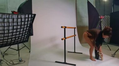 Parlak bir dans stüdyosunda, güzel bir kadın poz verirken ve dans etmeye hazırlanırken duruşunu ve zarafetini gösterir. Atmosfer sanatsal ve ilham verici. Stüdyo ekipmanları yaratıcı çevreyi geliştiriyor..