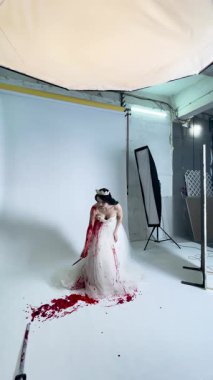 Kırmızı aksanlı göz kamaştırıcı bir gelinlik giymiş bir gelin sahne arkasına hazırlanıyor ve sanatsal bir an yaratıyor..