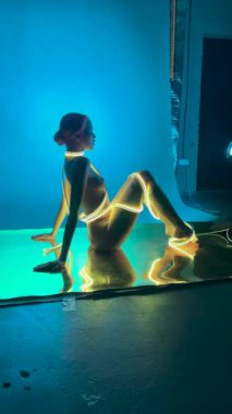 Bir kadın parıldayan iç çamaşırlarıyla zarif bir poz veriyor, sahne arkasında yaratıcılık sergiliyor..