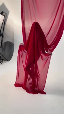 Bir kadın sahne arkasında güzelliğini ve özgüvenini vurgularken saf kırmızı iç çamaşırlarıyla zarifçe poz verir..