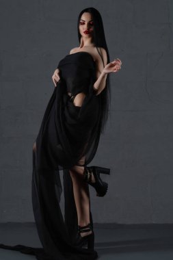 Çekici bir kadın zarif siyah iç çamaşırlarıyla poz verir. Zarif kumaşla örtülmüş. Tarzı ve özgüveni ön plana çıkar..