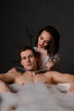 Erkek ve kadın yatakta rahatlar, birbirlerine eşlik ederken ve yakınlaşırken selfie çekerler..