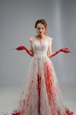 Kana bulanmış gelinlik giymiş bir gelin, bir katana kullanır. Güzellik ve dehşetin ürkütücü bir karışımını somutlaştırır..