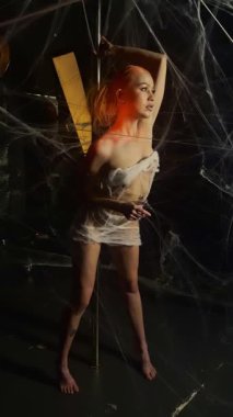 Kırmızı giyinmiş çarpıcı bir kadın büyük bir ağa takıldı. Yaratıcı bir ortamda güzelliğini ve sanatını sergiliyor..