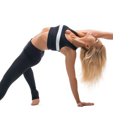 Parlak bir stüdyoda spor salonunda dinamik bir pozda bir kadın esnekliğini sergiliyor..