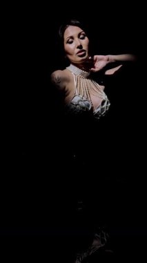 Zarif bir kadın loş bir stüdyoda spagetti yiyor büyüleyici bir atmosferde güzellik ve moda sergiliyor..