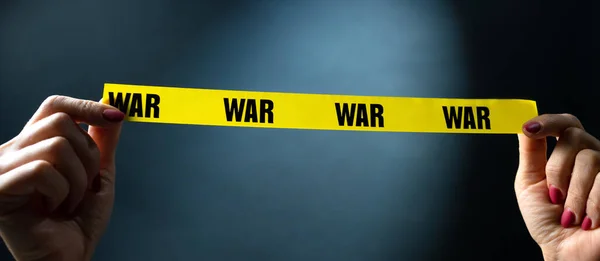 手拿着黄色带子 上面印有战争文字 象征着安全和停止冲突 危险和真相的概念 — 图库照片
