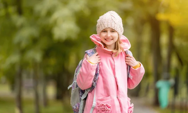 秋の公園で笑顔バックパック付きの美しい女子高生 散歩中にカメラを見ている未成年の子供 — ストック写真