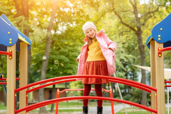 秋の屋外で遊び場に立つかわいい女の子の子供と笑顔 女性子供幸せな通りの肖像画 — ストック写真
