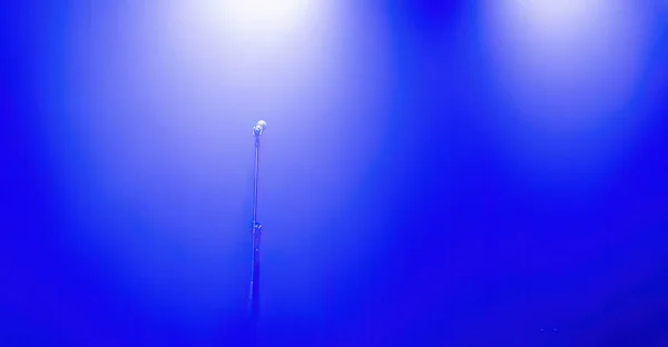 Light on a free music stage with mic, scene with blue spotlights on a background