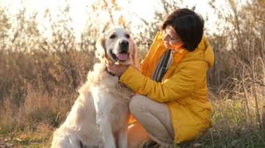 Golden Retriever köpeğini seven ve gün batımında gülümseyen bir kız. Evcil köpek labrador 'u olan genç bir kadın.