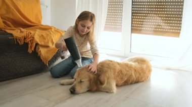 Mutlu küçük kız evdeki ıslak Golden Retriever köpeğine kurutucuyu üflüyor. Köpek ve çocuk banyodan sonra.