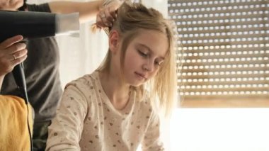 Anne evde küçük kızını saç kurutma makinesiyle kurutuyor. Banyodan sonra çocuk.