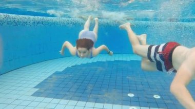 Şirin küçük kız ve babası havuzda yüzüyorlar.