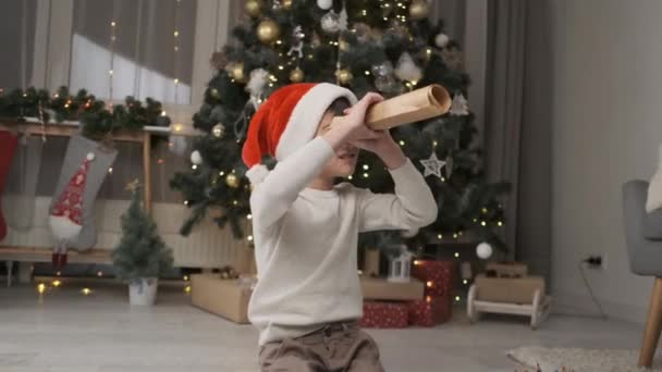 Kleiner Junge Mit Rotem Hut Der Hause Unter Dem Weihnachtsbaum — Stockvideo