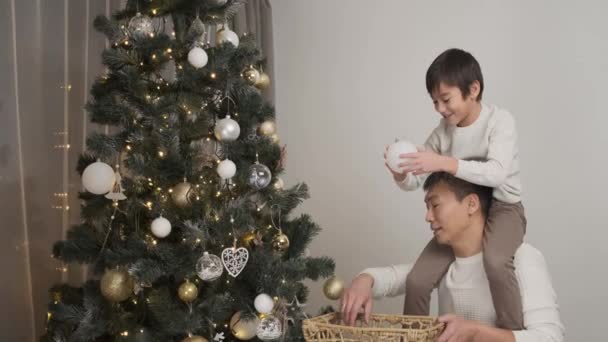 Menino Feliz Pendurado Bolas Para Árvore Natal Enquanto Sentado Nos — Vídeo de Stock