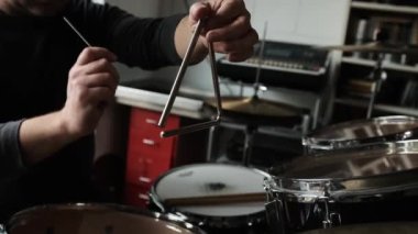 İnsan eli müzik üçgeninde metal sopayla dövüyor. Kayıt stüdyosunda geleneksel enstrümanlı müzisyen