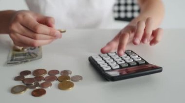 Çocuk para sayıyor ve euro 'yu hesap makinesine yatırıyor. Finans eğitimi sırasında tasarruf yapan çocuk elleri
