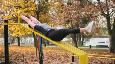 Spor yapan sporcu kız sonbahar parkında bacak kaldırıyor. Genç spor kadını doğada dışarlarda egzersiz yapıyor.