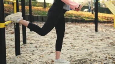 Fitness kızı dışarıda bacak egzersizi yapıyor. Güz parkında spor yaparken genç bir kadın.
