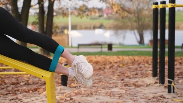 健身女孩在秋季公园用弹性橡皮筋做腿部锻炼 户外运动的妇女 — 图库视频影像