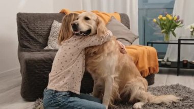 Prematüre kız evde yerde oturmuş Golden Retriever köpeğine sarılıyor. Tatlı bayan çocuk, evcil köpeğini oturma odasında okşuyor.