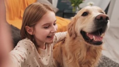 Golden Retriever köpekli küçük kız sosyal medya için video bloğu içeriği kaydediyor. Köpek besleyen güzel çocuk blog videosu yapıyor.
